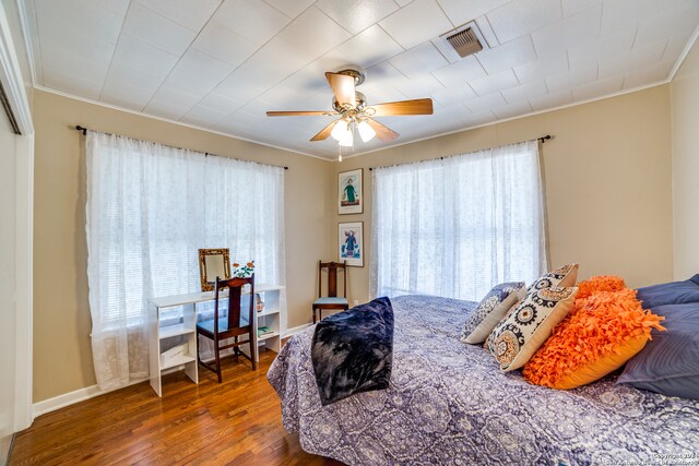 bedroom with dark wood-type flooring, ceiling fan, and ornamental molding