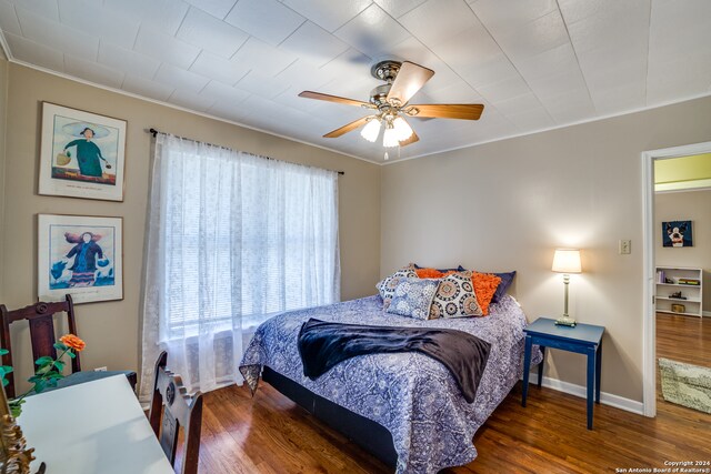 bedroom with ornamental molding, dark hardwood / wood-style floors, and ceiling fan