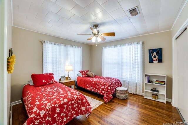 bedroom featuring ceiling fan, crown molding, multiple windows, and dark hardwood / wood-style flooring