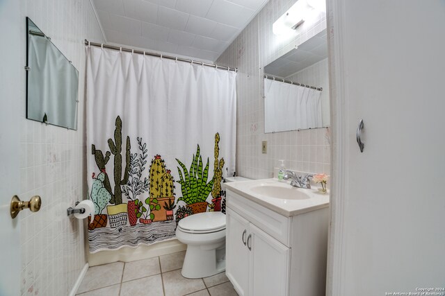 bathroom featuring vanity, toilet, tile patterned floors, and tile walls