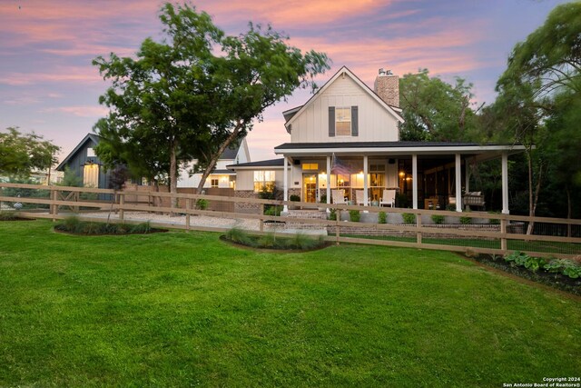 back house at dusk featuring a lawn