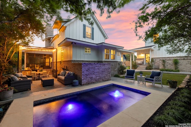 back house at dusk featuring a patio area and outdoor lounge area