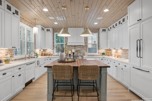 kitchen with wood counters, a center island, white cabinets, and plenty of natural light