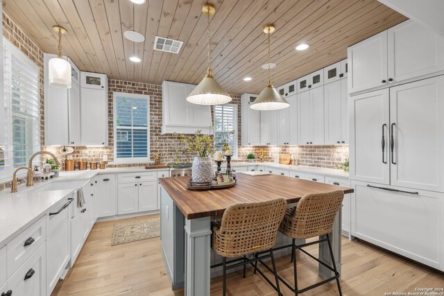 kitchen with wood counters, a center island, a breakfast bar area, and white cabinets