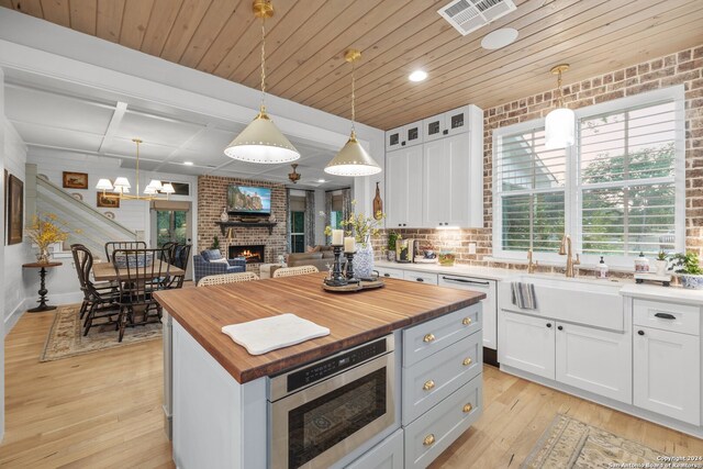 kitchen featuring a fireplace, a center island, hanging light fixtures, light hardwood / wood-style floors, and white cabinets