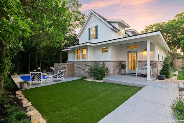 back house at dusk featuring a patio and a yard