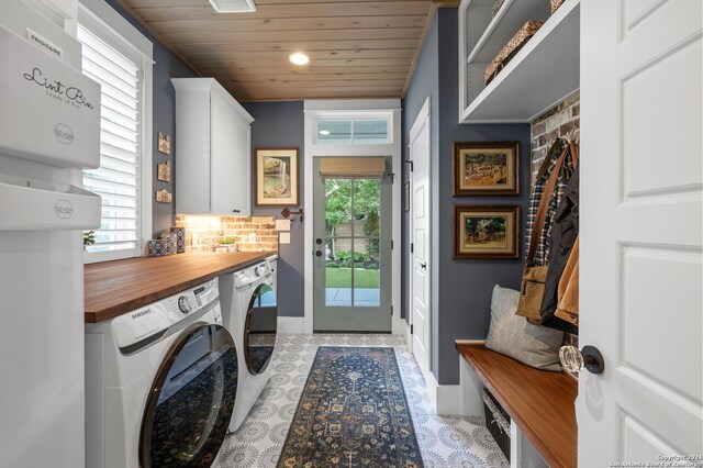 clothes washing area with light tile patterned floors, washing machine and dryer, cabinets, and wooden ceiling