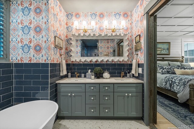 bathroom featuring vanity, a tub to relax in, hardwood / wood-style flooring, and tile walls