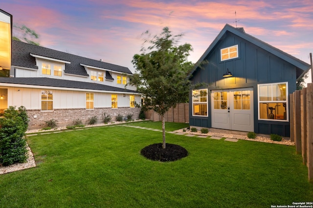 back house at dusk featuring a yard