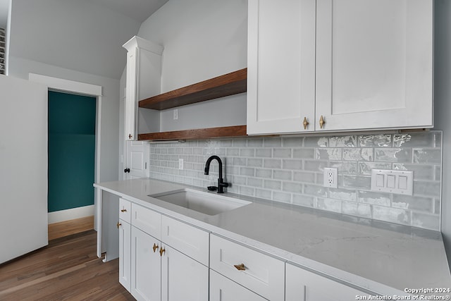 kitchen featuring sink, white cabinetry, dark wood-type flooring, light stone counters, and decorative backsplash