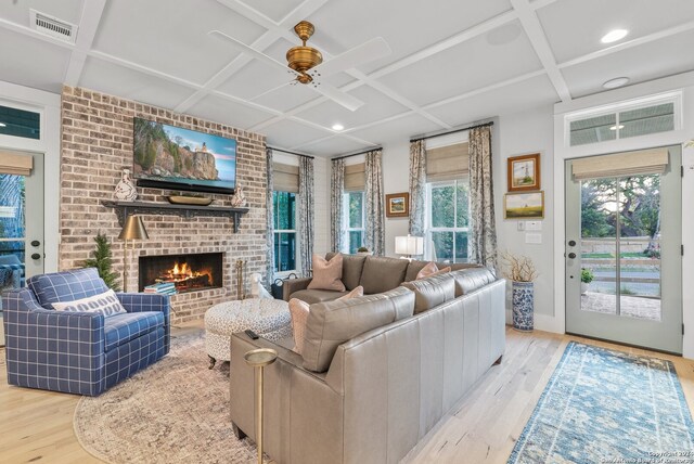 living room featuring coffered ceiling, a healthy amount of sunlight, and light hardwood / wood-style flooring