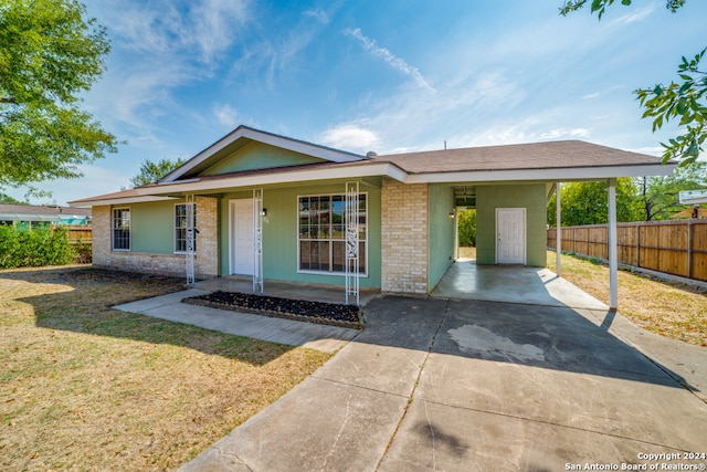 ranch-style home featuring concrete driveway, covered porch, a front yard, fence, and an attached carport