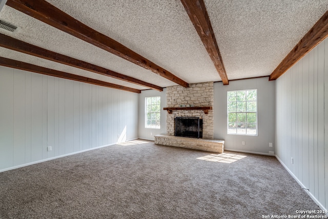 unfurnished living room with a large fireplace, a textured ceiling, visible vents, and beam ceiling