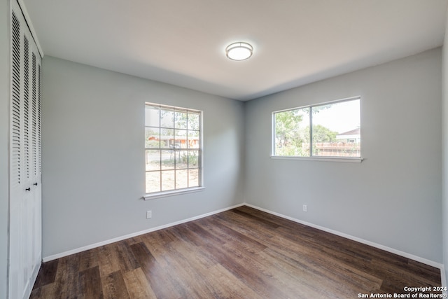 unfurnished bedroom featuring dark wood-style flooring, a closet, and baseboards