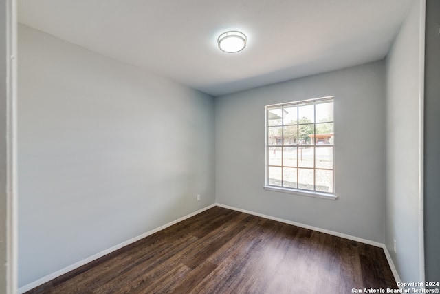 empty room featuring dark wood-style floors and baseboards