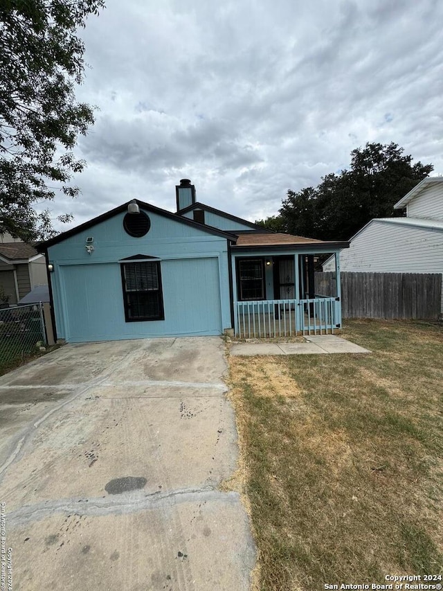 view of front of house featuring covered porch, a front yard, and a garage