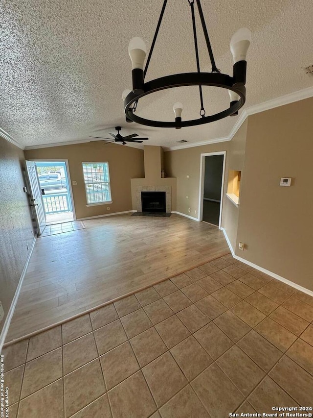 unfurnished living room featuring ornamental molding, ceiling fan with notable chandelier, a textured ceiling, and light hardwood / wood-style floors