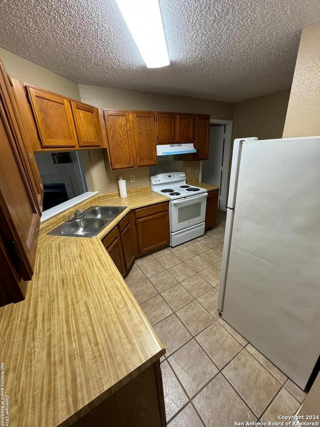 kitchen featuring a textured ceiling, sink, light tile patterned floors, and white appliances