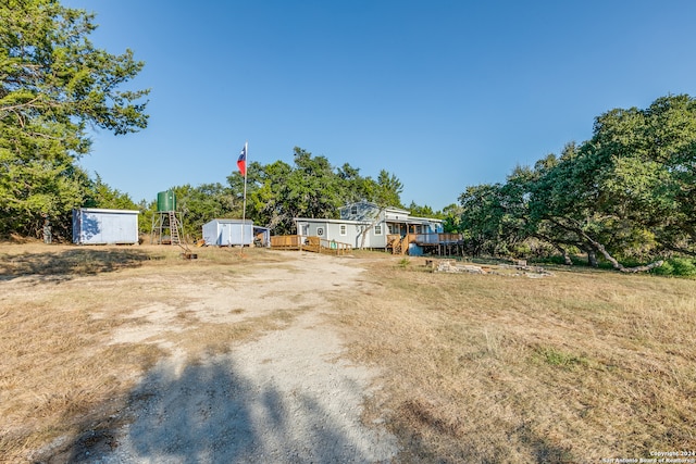 view of yard featuring a wooden deck and a storage unit