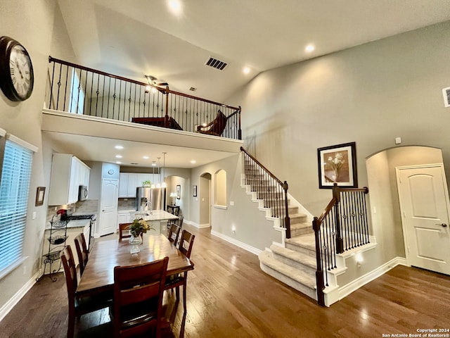 dining space featuring hardwood / wood-style floors and high vaulted ceiling