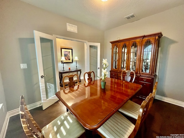 carpeted dining space with a textured ceiling and vaulted ceiling