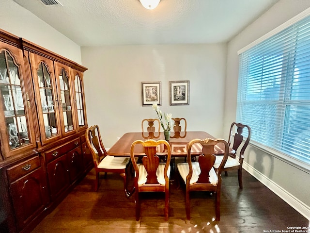 dining room with a textured ceiling and dark hardwood / wood-style flooring