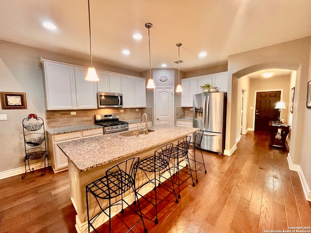 kitchen featuring sink, light wood-type flooring, stainless steel appliances, white cabinets, and a center island with sink