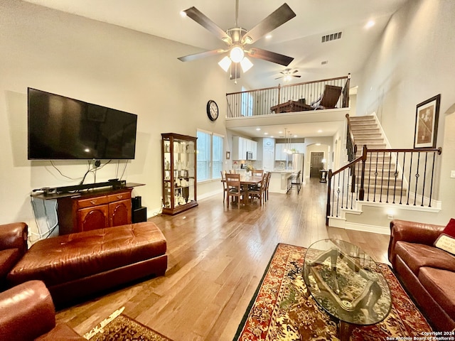 living room with hardwood / wood-style floors, a high ceiling, and ceiling fan