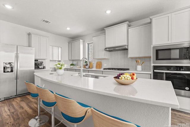 kitchen with dark hardwood / wood-style flooring, stainless steel appliances, a kitchen island with sink, and sink