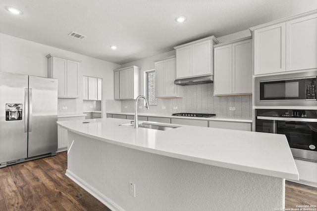 kitchen with sink, dark hardwood / wood-style flooring, a center island with sink, white cabinets, and appliances with stainless steel finishes