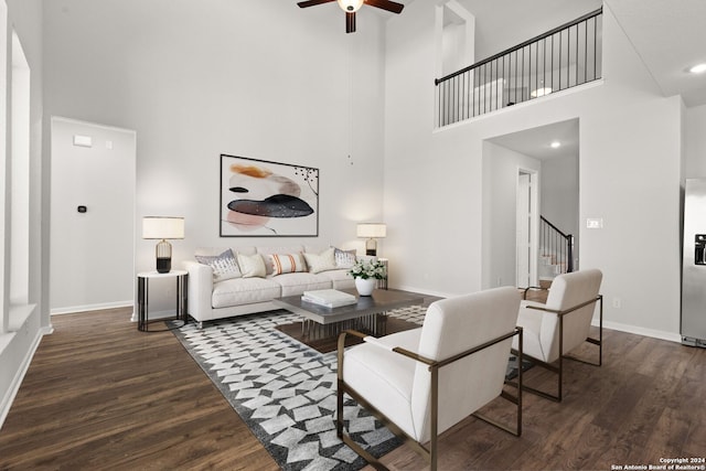 living room featuring ceiling fan, dark wood-type flooring, and a high ceiling