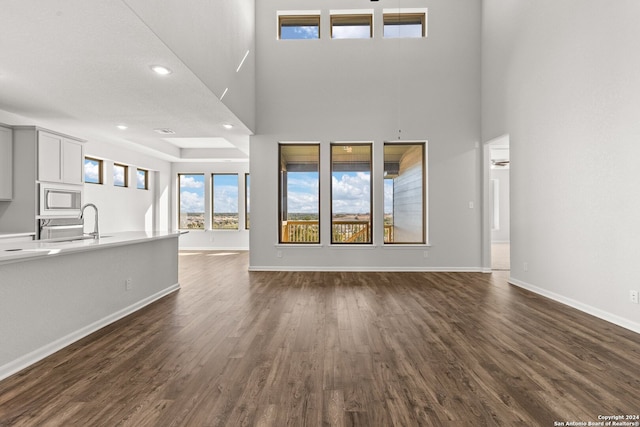 unfurnished living room with a textured ceiling, dark hardwood / wood-style flooring, a high ceiling, and sink