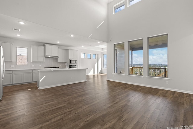 unfurnished living room featuring dark hardwood / wood-style floors, a towering ceiling, and sink