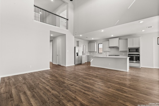 unfurnished living room featuring a high ceiling, dark hardwood / wood-style floors, and sink