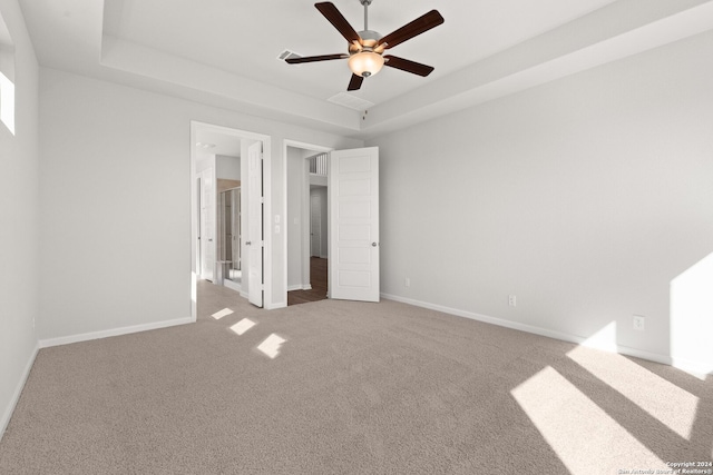 unfurnished bedroom featuring carpet, a raised ceiling, and ceiling fan