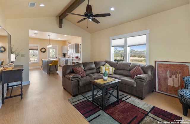 living room featuring light hardwood / wood-style floors, lofted ceiling with beams, ceiling fan, and a wealth of natural light