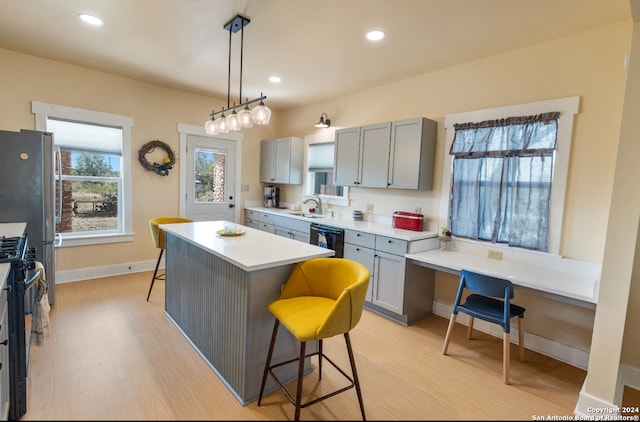 kitchen featuring a breakfast bar, sink, a kitchen island, and gray cabinets