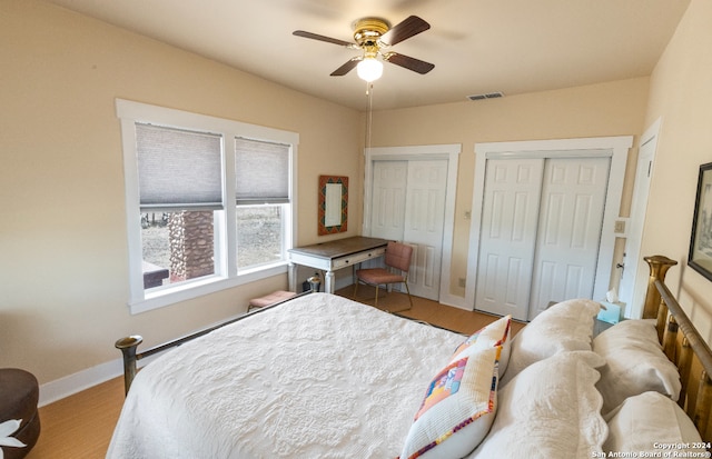 bedroom featuring light hardwood / wood-style floors, multiple closets, and ceiling fan