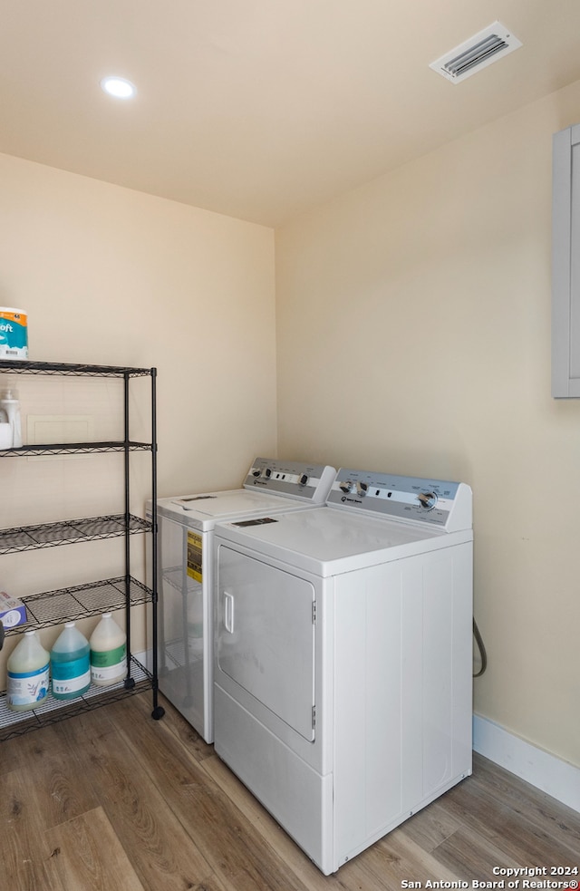 clothes washing area featuring hardwood / wood-style floors and washer and clothes dryer