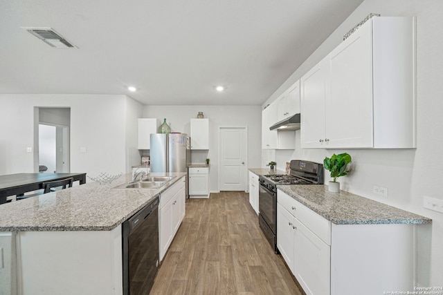 kitchen featuring light stone countertops, black appliances, an island with sink, white cabinetry, and light hardwood / wood-style flooring