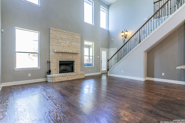 unfurnished living room with a high ceiling, a healthy amount of sunlight, and dark hardwood / wood-style flooring