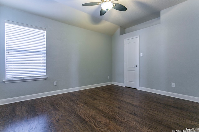 empty room with ceiling fan, vaulted ceiling, and dark hardwood / wood-style floors