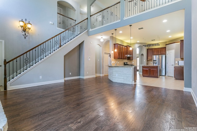 unfurnished living room featuring a towering ceiling, sink, and wood-type flooring