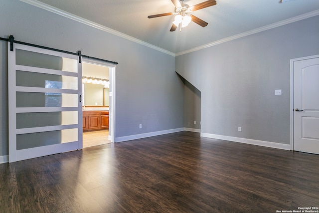 spare room with dark wood-type flooring, crown molding, a barn door, and ceiling fan