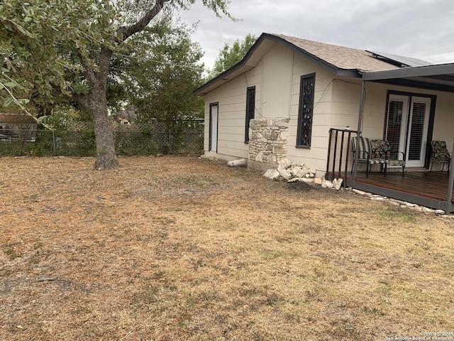 view of side of home with a lawn, a wooden deck, and fence