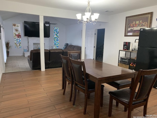 dining area featuring a fireplace, light wood-style floors, visible vents, and ceiling fan with notable chandelier