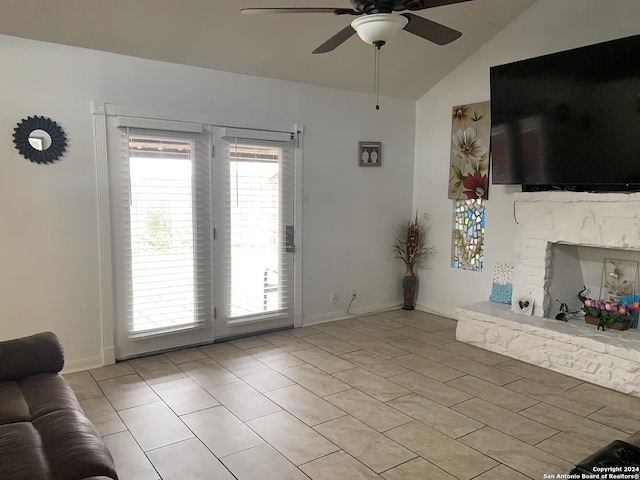 living area featuring vaulted ceiling, light tile patterned floors, baseboards, a fireplace, and ceiling fan