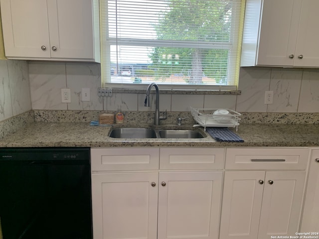 kitchen featuring light stone countertops, black dishwasher, sink, and white cabinets