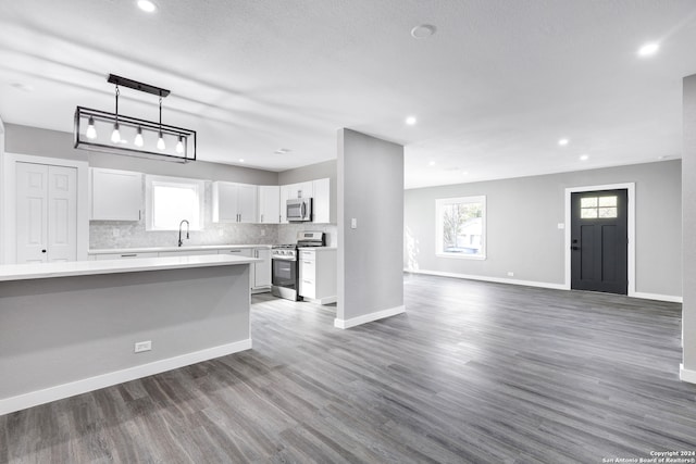 kitchen with white cabinets, dark hardwood / wood-style flooring, a textured ceiling, pendant lighting, and stainless steel appliances