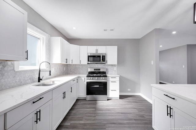 kitchen with appliances with stainless steel finishes, white cabinetry, sink, and dark hardwood / wood-style flooring